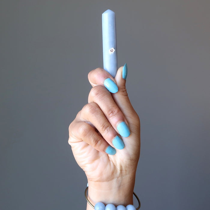 hand wearing angelite bracelet and holding blue angelite wand