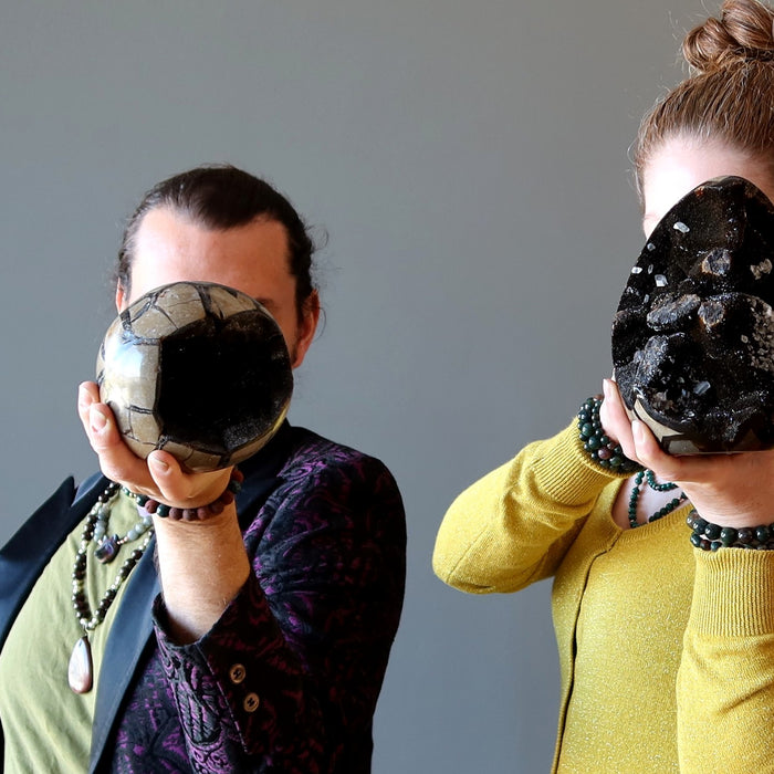 people holding septarian stones in front of faces