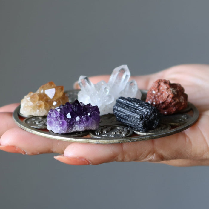 hand holding chakra crystal clusters