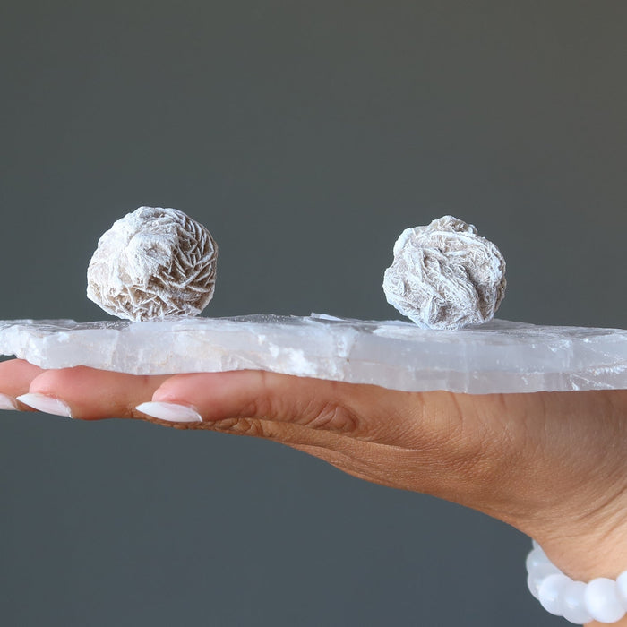 hand holding desert rose on selenite slab