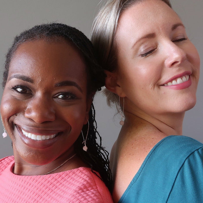 two women back to back wearing matching earrings