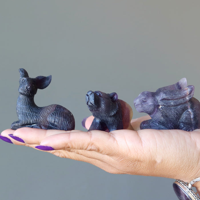 hand holding fluorite deer, bear, rabbit