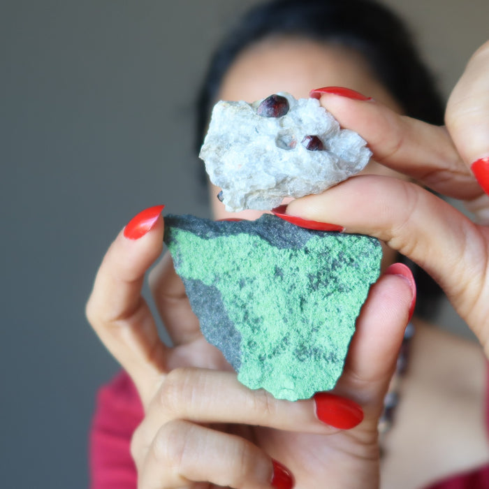 woman holding red and green garnet raw clusters