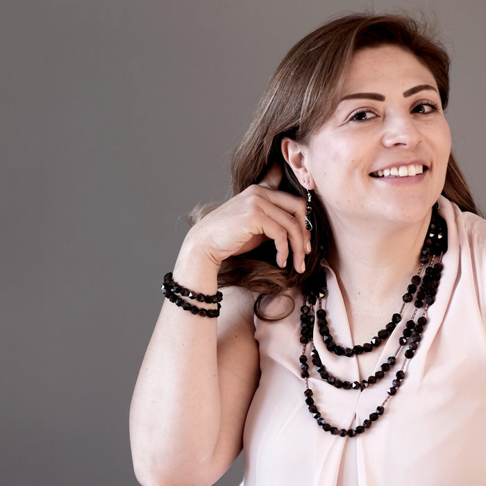 woman modeling faceted garnet earrings, necklaces, bracelets