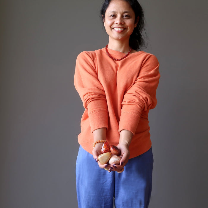 sheila of satin crystals holding orange crystals at her sacral chakra