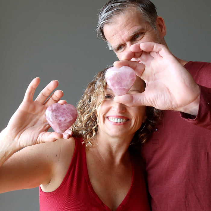 man and woman holding pink rose quartz hearts