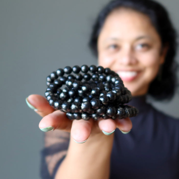 sheila of satin crystals holding pile of jet bracelets