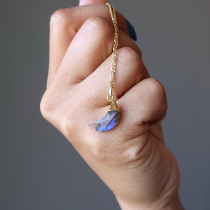 hand holding a faceted labradorite new moon necklace