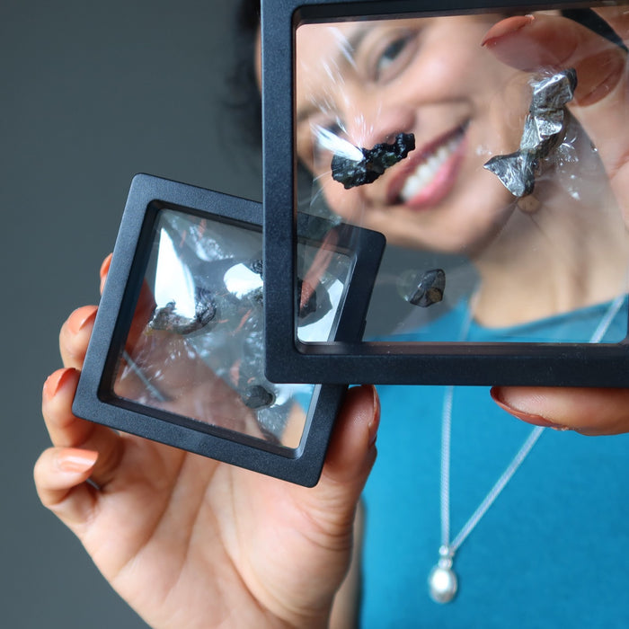 female holding suspension frames filled with meteorites
