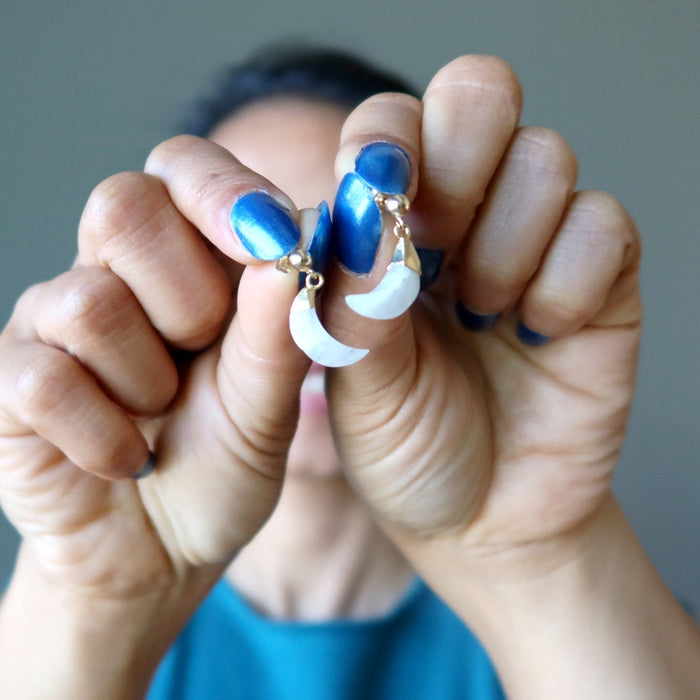 woman holding moonstone moon earrings