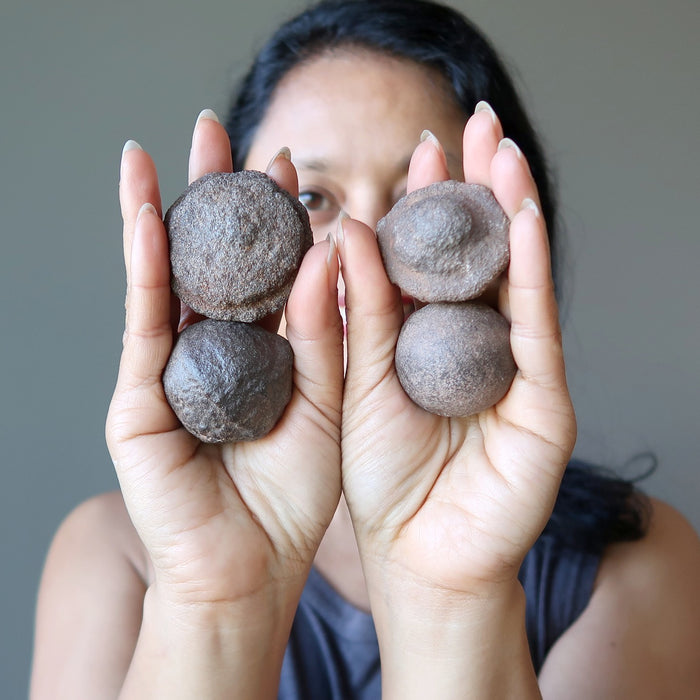 sheila of satin crystals holding 4 moqui marble stones in the palm of her hands