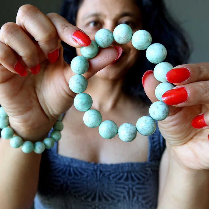 woman holding and wearing chrysoprase bracelets