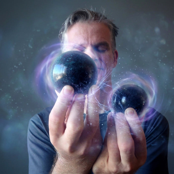 man with eyes closed holding two ruby kyanite spheres