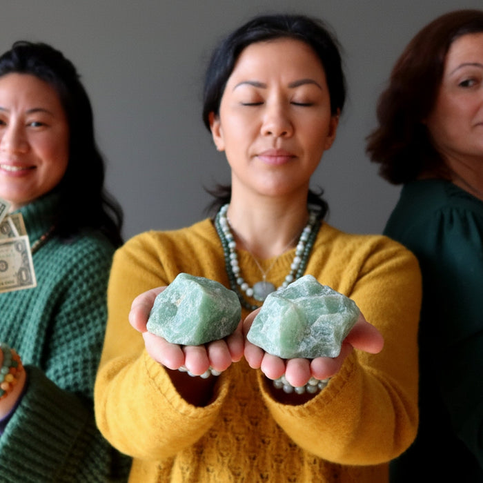 women holding green calcite stones and money