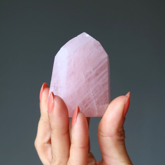 hand holding up a pink rose quartz tower