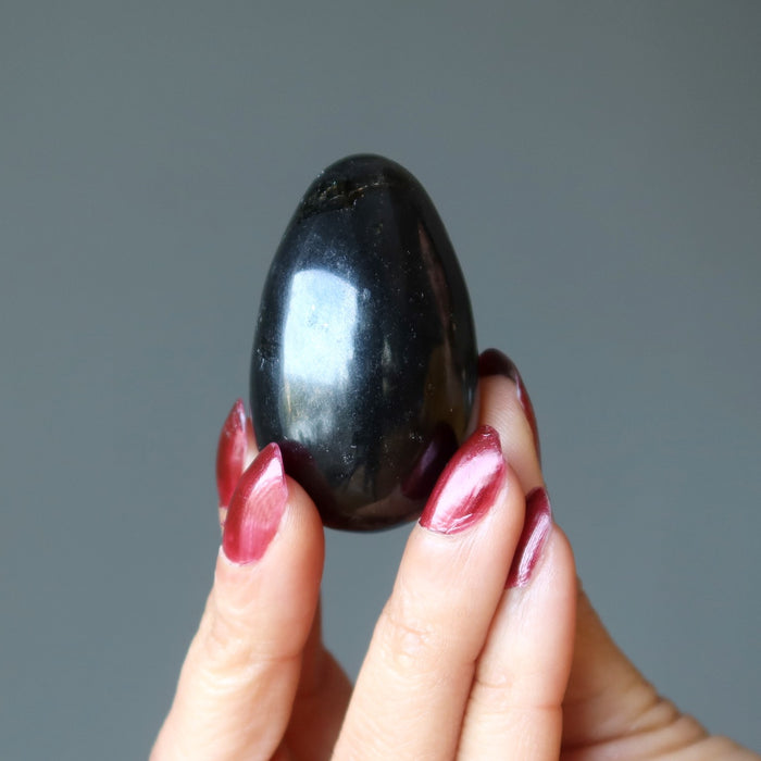 hand holding up a black tourmaline egg