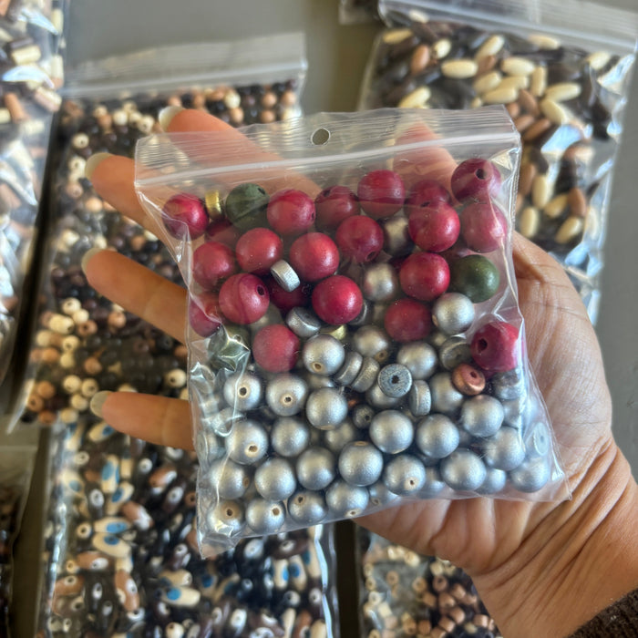 Hand holding a clear plastic bag filled with multicolored beads.