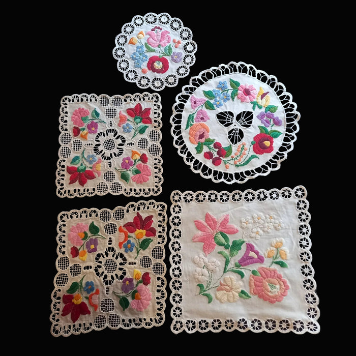 Set of embroidered doilies with floral patterns on a black background