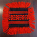 Square woven fabric with red pattern and fringes handmade in hungary on a dark background
