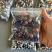 Hand holding a bag of assorted beads with more bags in the background.