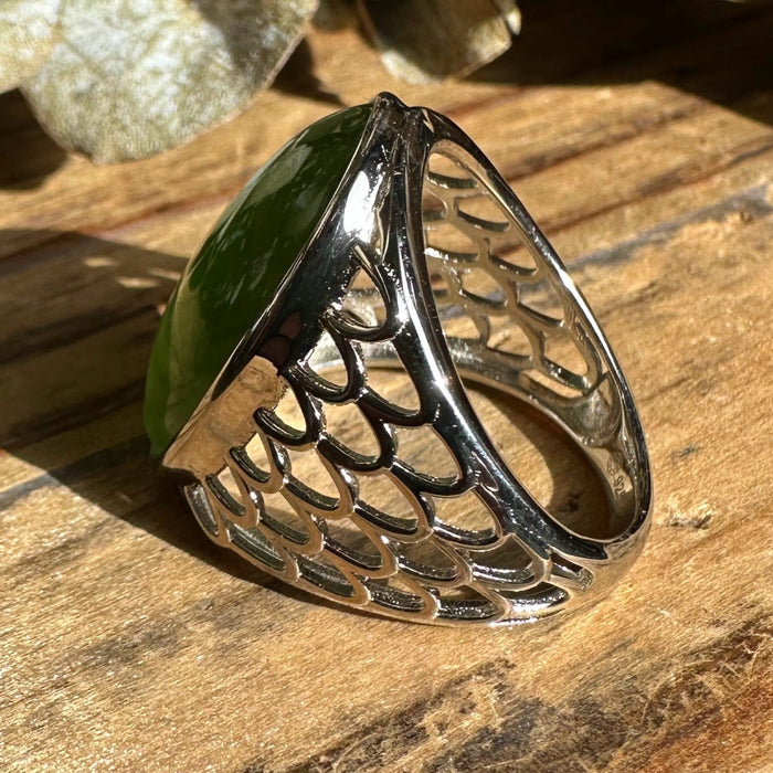 Silver ring with a green jade on a wooden surface