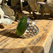 Silver ring with a green jade stone on a wooden surface with leaves in the background
