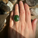 Green jade stone ring on a hand with a natural background