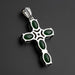 Silver cross pendant with green stones on a wooden surface