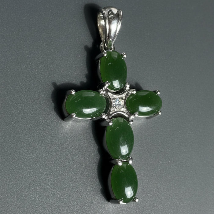 Green cross pendant with silver accents on a wooden surface