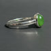 Silver ring with a green stone on a gray surface