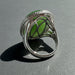 Silver ring with green jade on a wooden surface