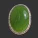 Green jade ring with silver band on a wooden surface