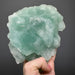 Hand holding a large green fluorite crystal against a dark background