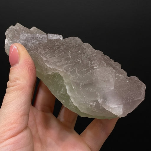 Hand holding a crystal against a light background