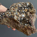 Mineral sample held by a hand against a gray background