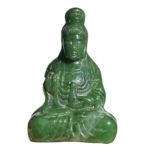 Green jade statue of a seated figure on a wooden surface with a light green background