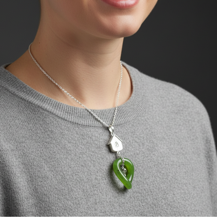 Green jade pendant with silver house and heart design on a dark background