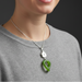 Green jade pendant with silver house and heart design on a dark background