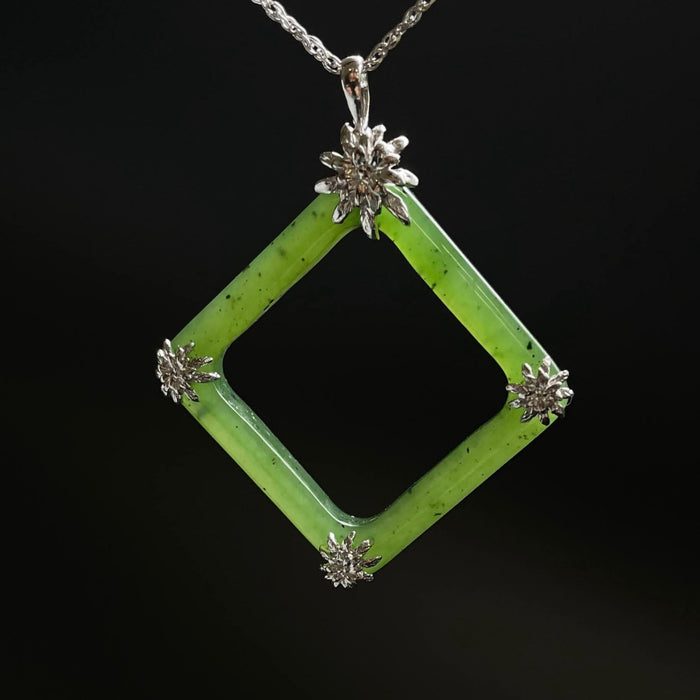 Green square jade pendant with floral elements on a black background