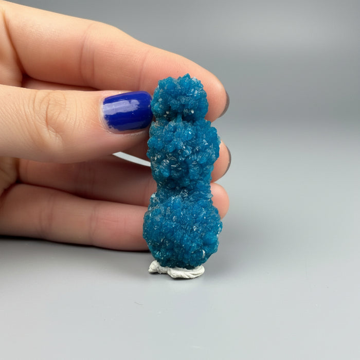 Blue crystal-like figurine held in a hand against a dark background