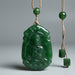 Green jade pendant with intricate design on a gray background