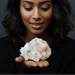 Woman holding a Zeolite crystal formation against a dark background