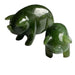 Two green jade pig figurines on a white background