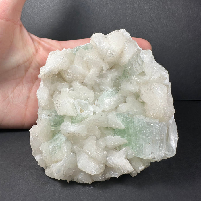 Hand holding a large crystal rock against a dark background