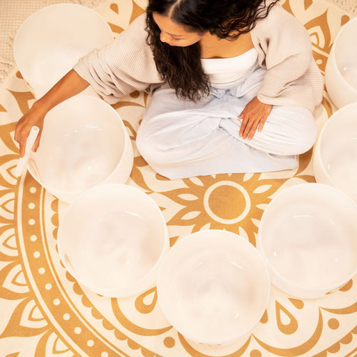Woman sitting on a patterned rug with white cushions