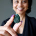 Person holding a green Moss Agate stone with a blurred background
