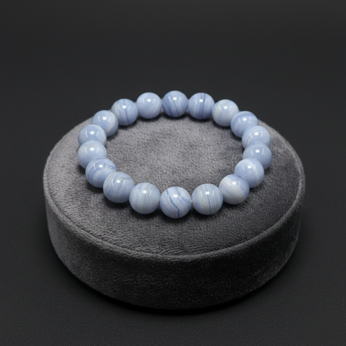 Blue lace agate beaded bracelet on a gray stand against a black background