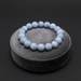 Blue lace agate beaded bracelet on a gray stand against a black background