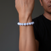 Person wearing a blue lace agate beaded bracelet on a dark background