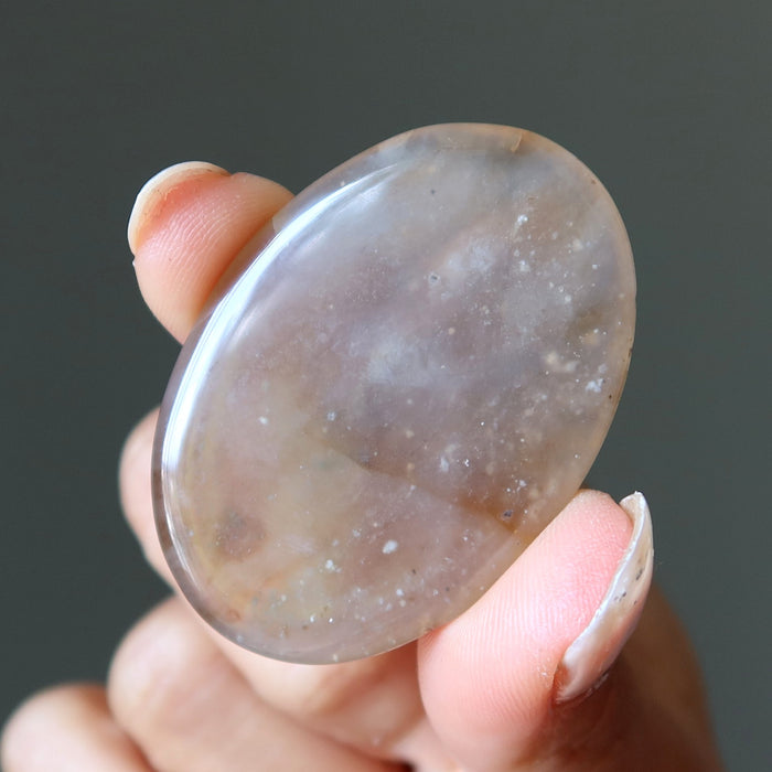 Hand holding a smooth, oval-shaped stone against a dark background